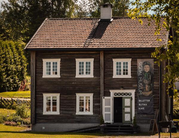 Den gamle lensmannsgården fra Plassane rommer i dag Sigdal Museums butikk, kafe og sommerutstillinger.